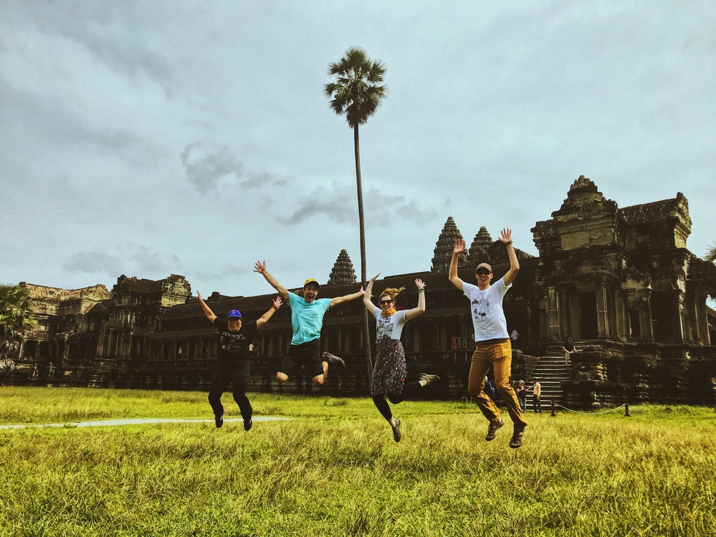 Four friends jump in excitement while traveling abroad in front of Ankor Wat Temple in Cambodia