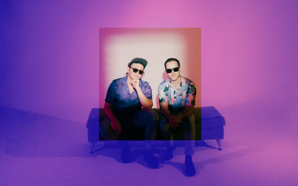 Househusband band members seated in a neon-lit studio during their Studio Lab photoshoot in Portland, Oregon