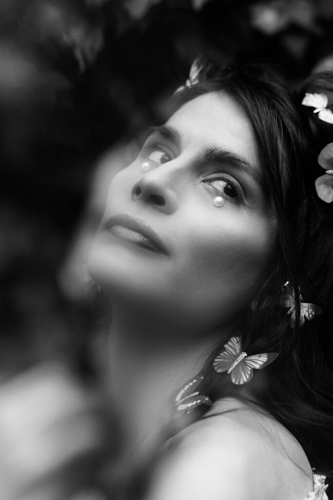 Black and white branding portrait featuring soft blur and butterfly accessories—capturing vulnerability and creative strength in a fine art style.