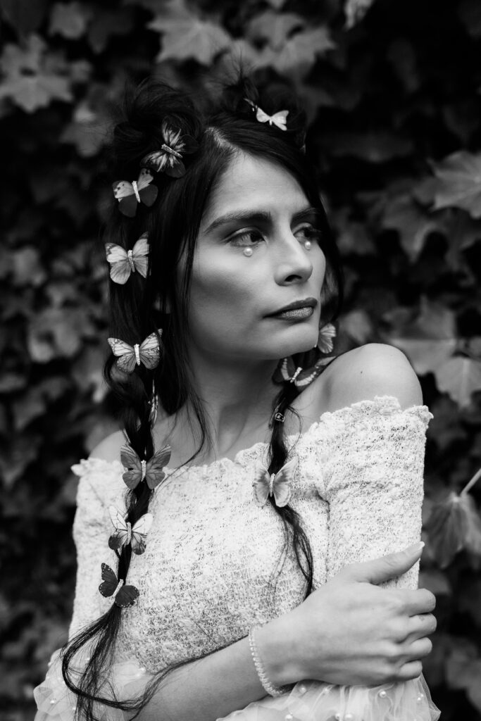 Black and white creative portrait with off-the-shoulder lace and detailed hair styling.