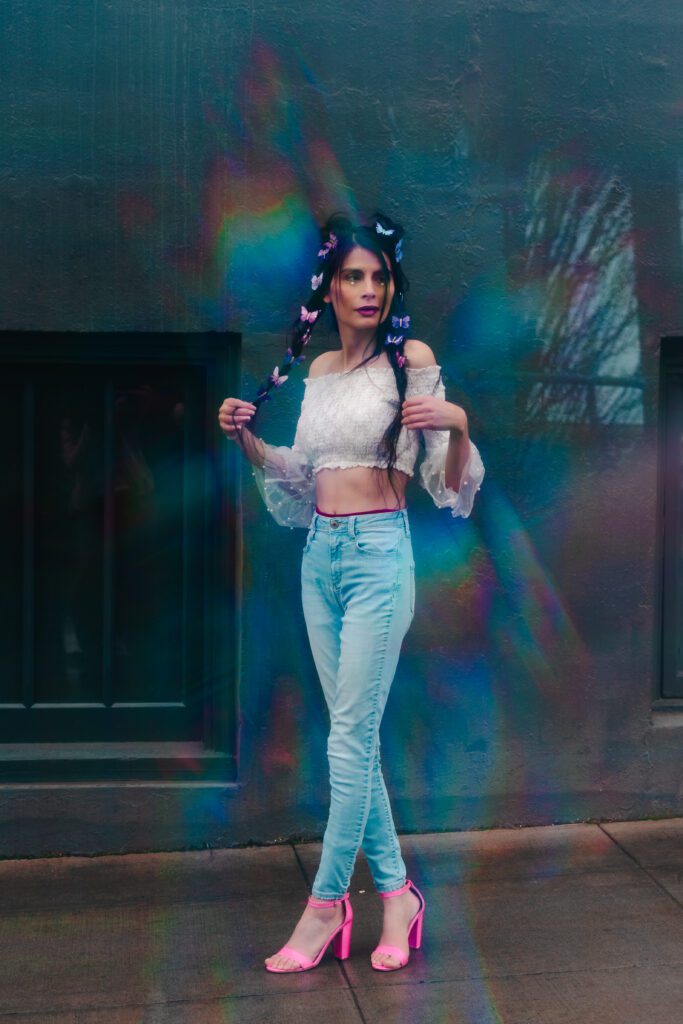 Creative portrait with rainbow lens flare, styled with pastels and butterflies.