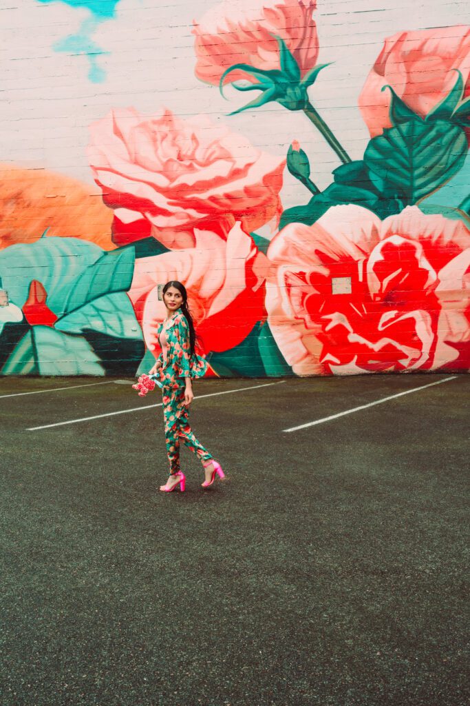 Branding portrait with floral backdrop, pink heels, and confident walking pose.