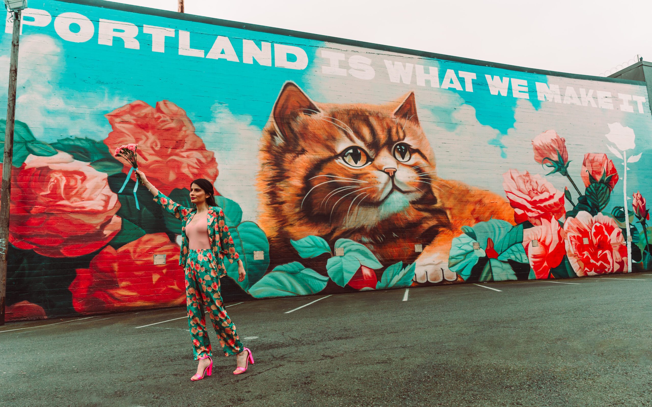 Woman posing in front of Cat Mural in PDX wearing pink and turquoise two piece outfit with soft glam makeup during her commercial headshot session with Mewphotovideo in Portland, Oregon.