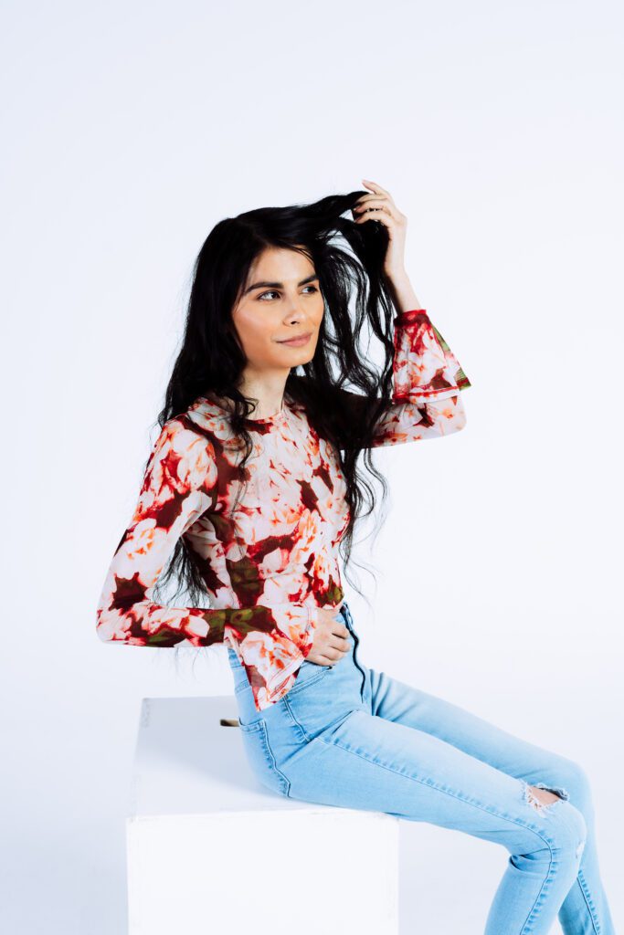 Strobe Photography of a woman in a floral blouse and light jeans, styled for commercial brand photography.