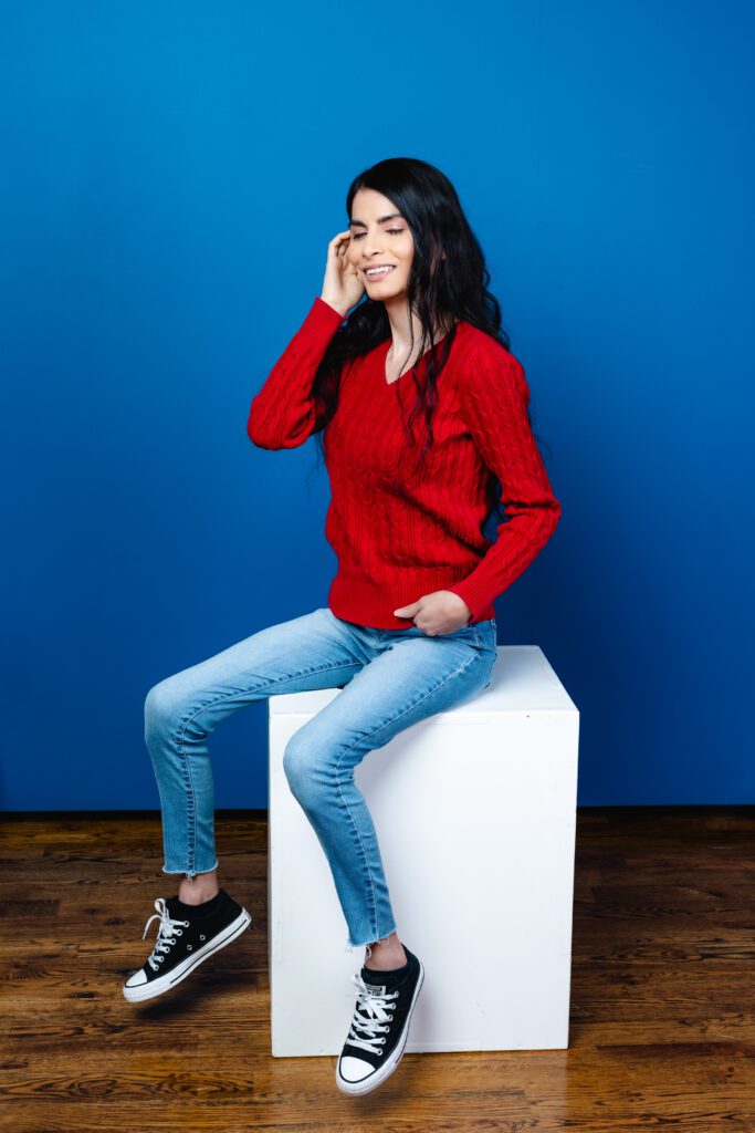 Friendly, smiling brand photo in a red sweater and jeans—ideal for creatives needing colorful headshots.