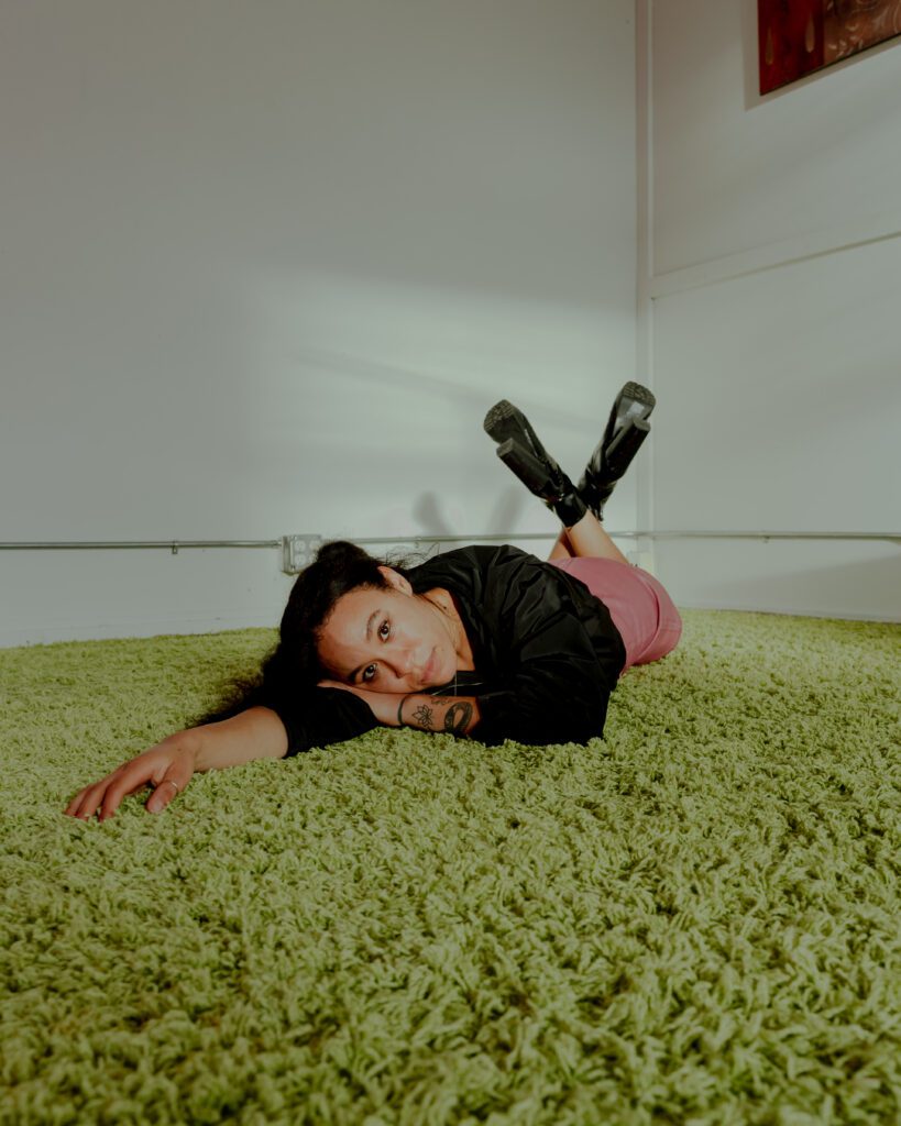 woman laying on green shag carpet in studio setting for expressive brand photo