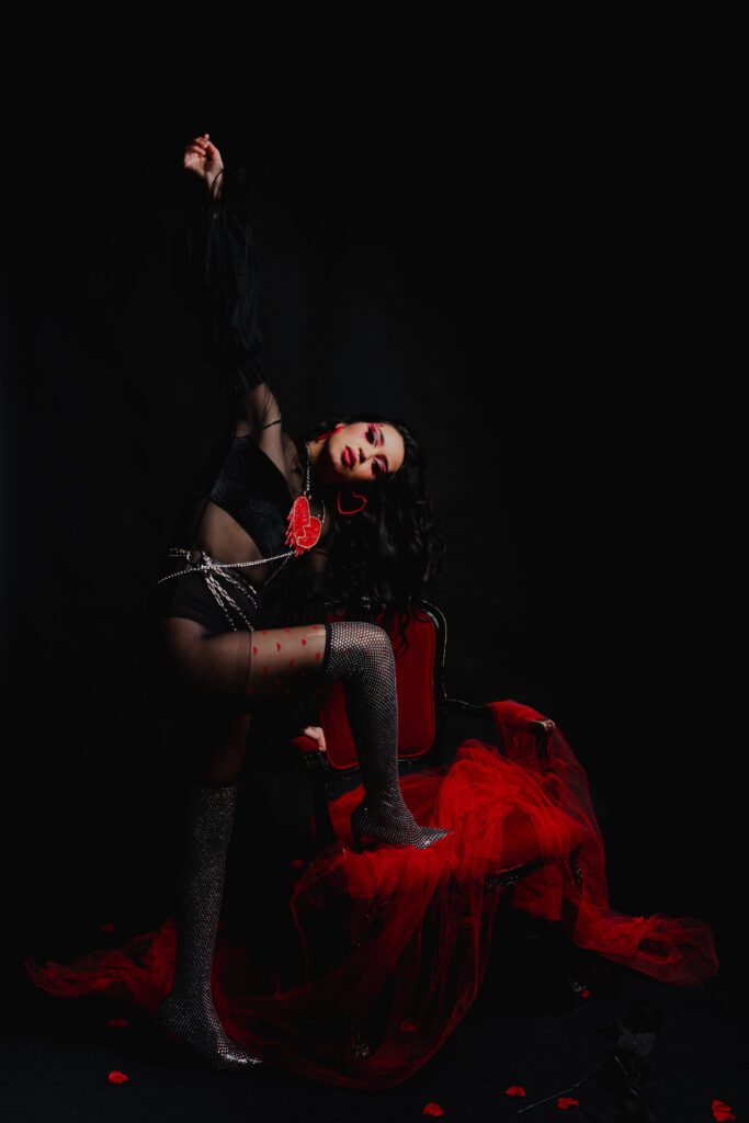 Client captured mid-motion in a flowing red gown and sparkling tights, framed against a black studio background with dynamic lighting in The Studio Lab by Mewphotovideo