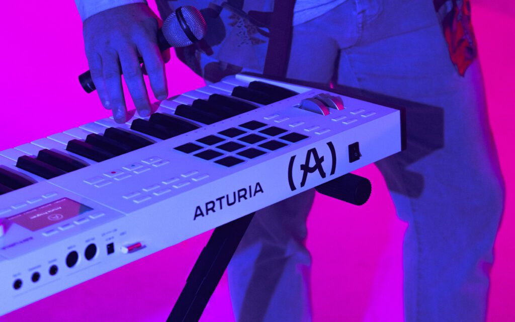 Close-up of Arturia keyboard and microphone in a pink-lit studio setup during a musician branding session with Mewphotovideo in Portland, Oregon