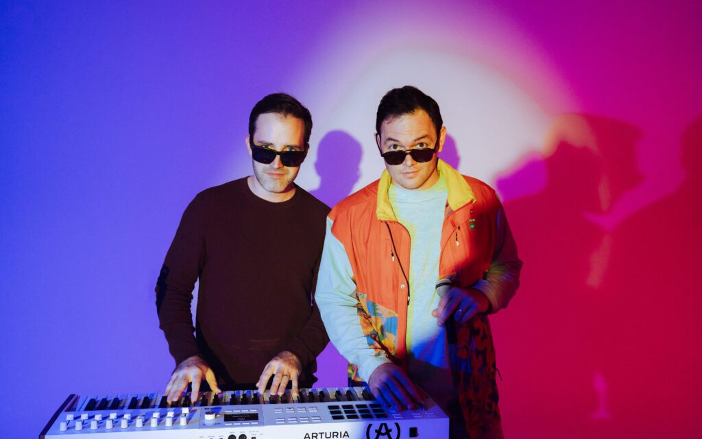 Members of Househusband playing an Arturia keyboard with dramatic colored lighting during their Portland artist branding photoshoot
