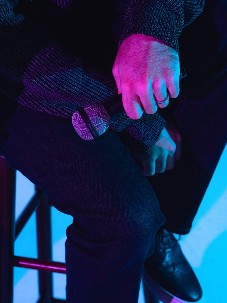 Detail shot of Househusband member holding a microphone under neon lighting during a Portland Studio Lab artist branding photoshoot