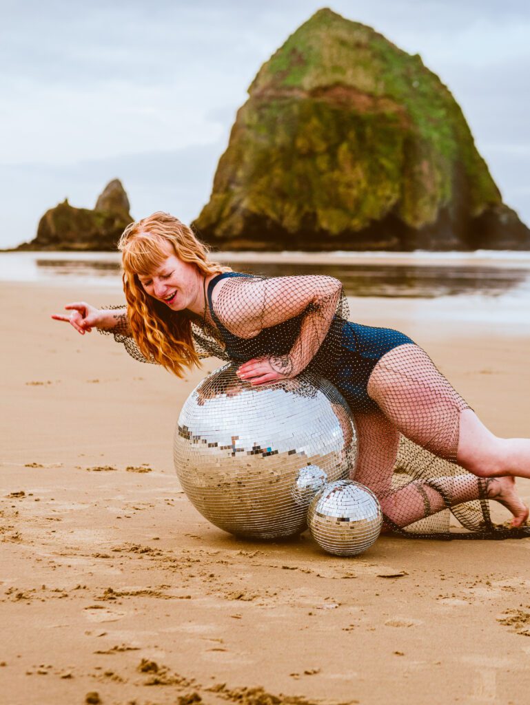 creative brand photo of woman on beach with disco ball and rock formations