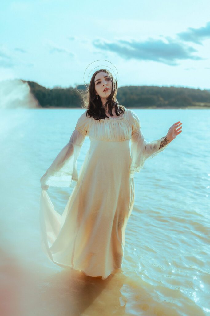 Client in flowing white dress standing in calm lake waters with soft glow and movement—captured during a golden hour Outdoor Adventure brand session