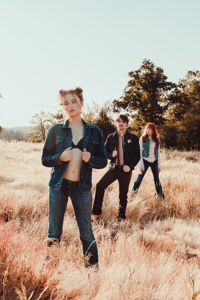 Group of young adults posing confidently in a golden grass field with sunlight and movement—part of a collaborative Outdoor Adventure brand session