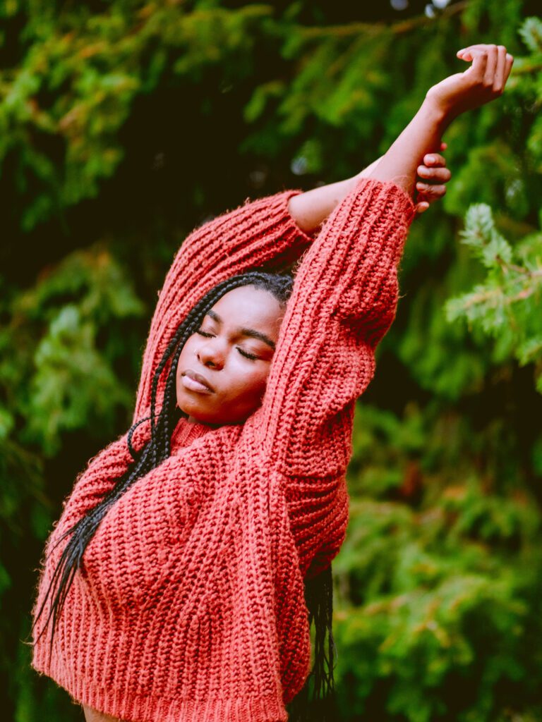 woman in red sweater stretching in forest during natural light branding session