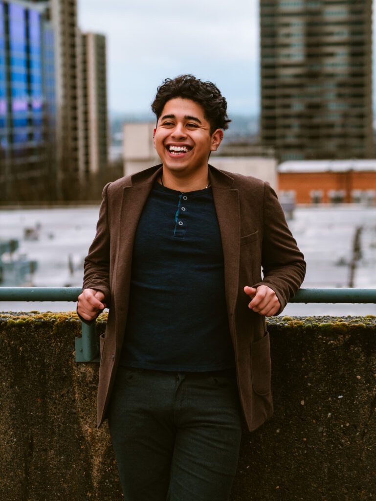 young male entrepreneur laughing confidently on rooftop with city skyline behind him