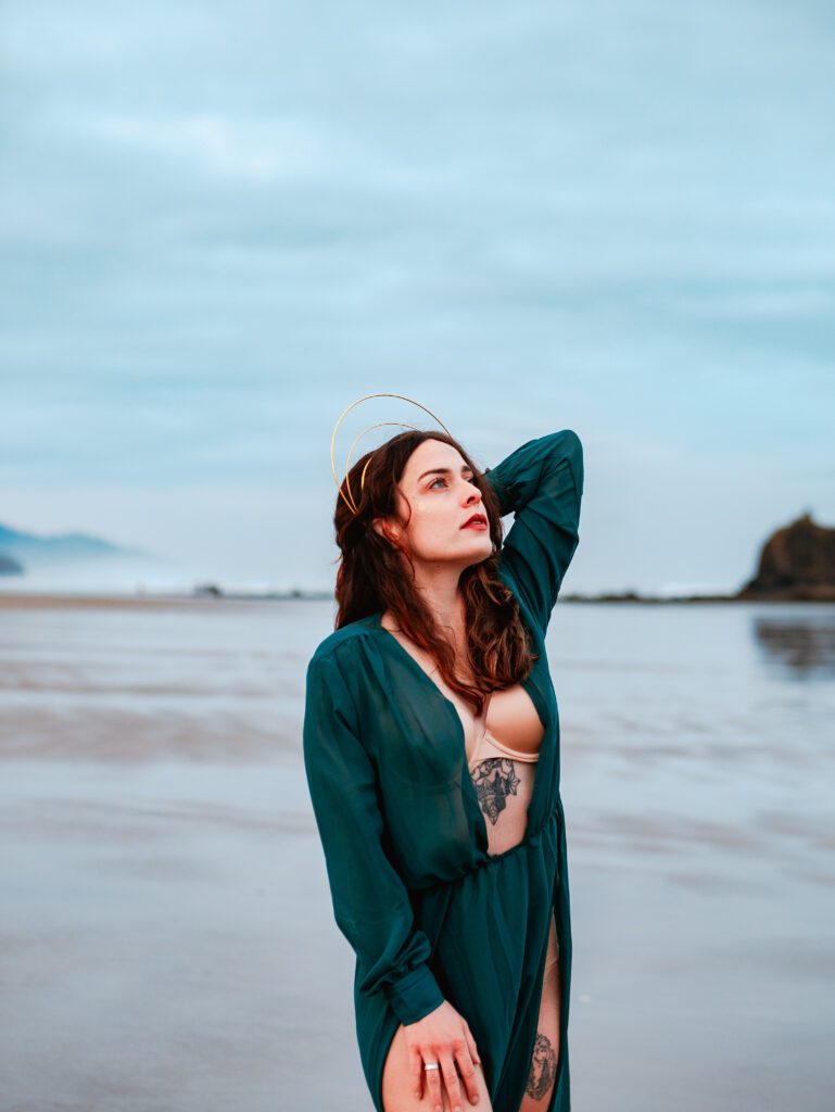 Client standing confidently on the Oregon coast in an emerald green dress, captured during an Outdoor Adventure session with cinematic styling