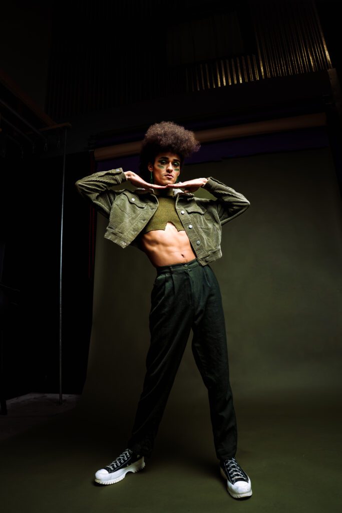 Person standing powerfully in cropped jacket and pants on moody studio set, lit for contrast and bold shadows in The Studio Lab session