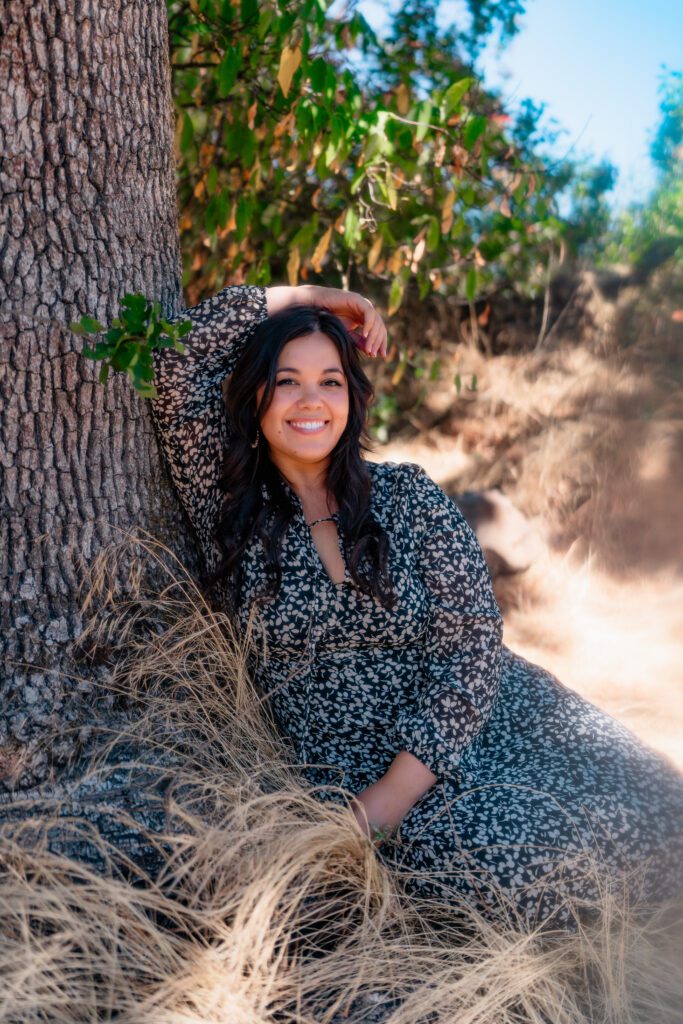 Artist smiling against tree trunk in natural light during a musician-focused branding photoshoot in Oregon