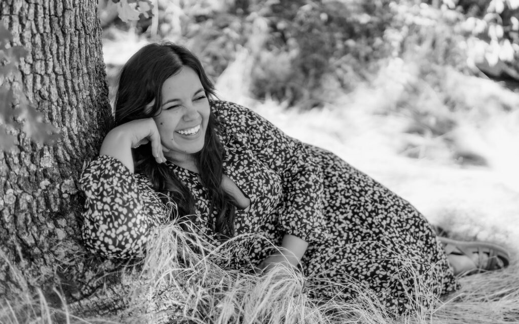 Black and white editorial-style photo of an artist reclining under a tree during a Portland brand session