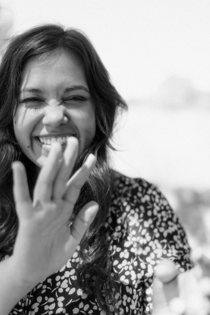 Candid close-up of a female artist laughing during a relaxed outdoor branding shoot in natural light