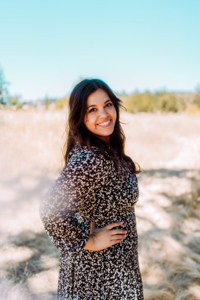 Mid-length portrait of a musician smiling in a field during a sunny outdoor branding session near Portland