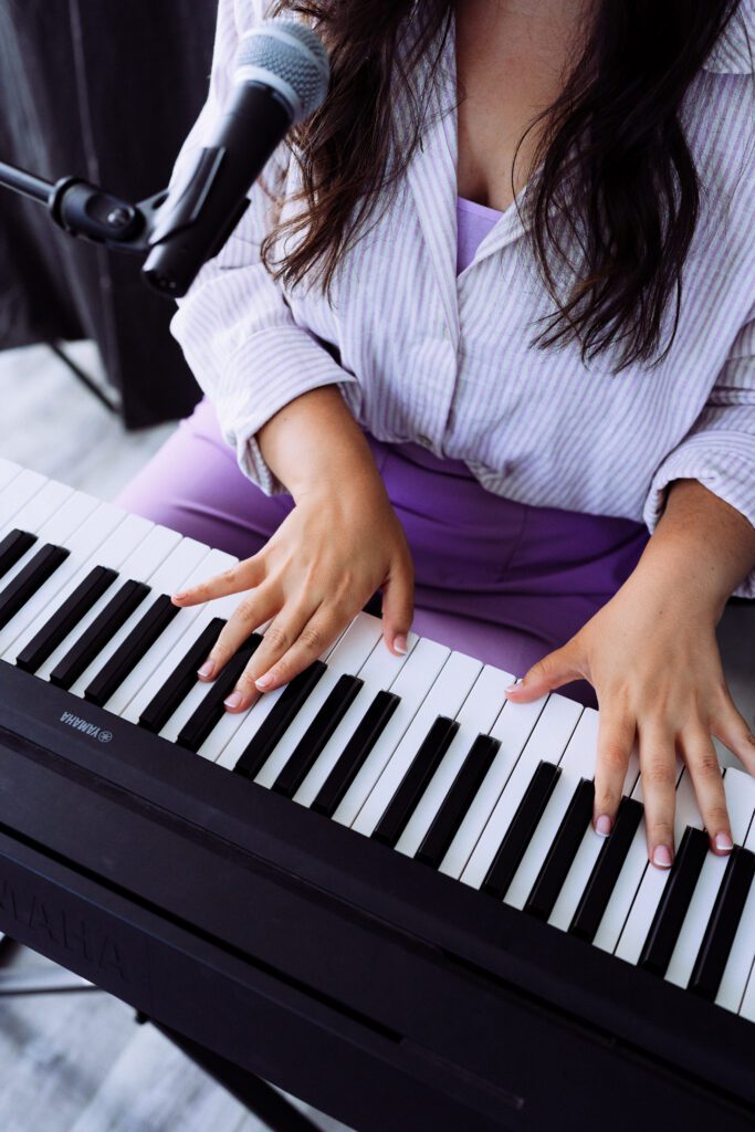 Close-up of musician’s hands at the keyboard wearing lilac pants during a personal branding shoot in Portland