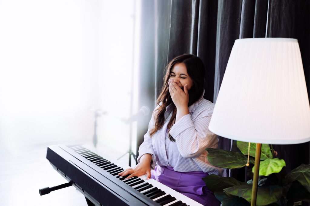 Artist in white blouse and purple pants at the keyboard, captured in natural light during a brand shoot