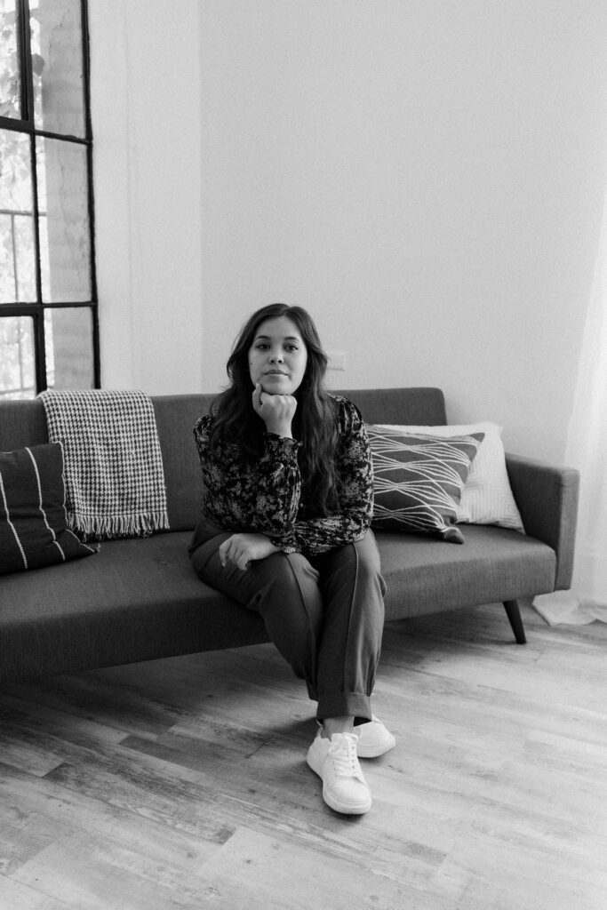 Black and white portrait of a musician in a seated pose on a sofa during a Portland branding photoshoot