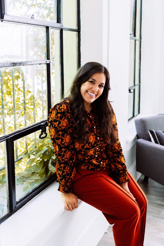 Smiling artist sitting by a large window in a creative lifestyle brand photoshoot in Portland