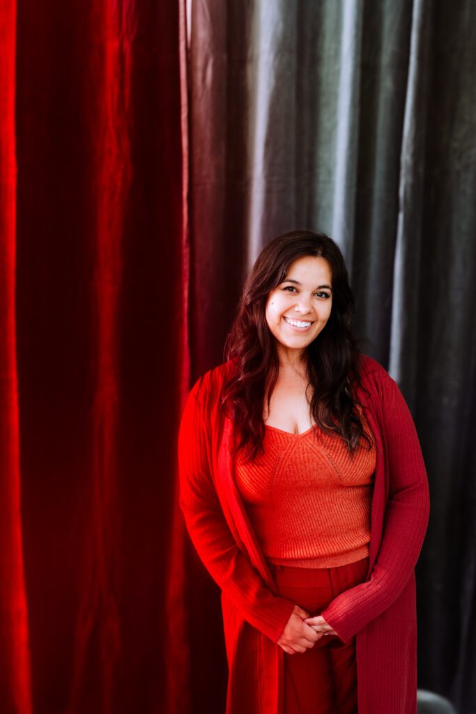 Personal branding portrait of a singer standing in front of red velvet curtains during Portland studio shoot