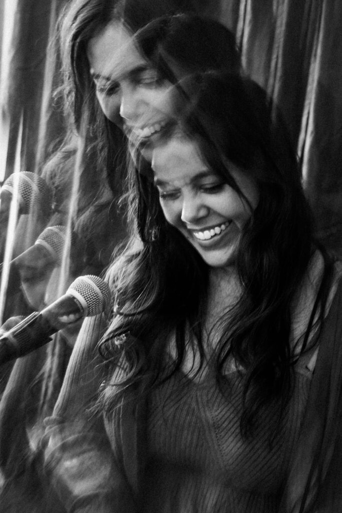 Black and white candid of a smiling music artist at microphone stand during branding session