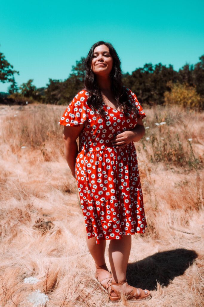 Artist in red floral dress standing in a golden field during a music brand photoshoot in Oregon
