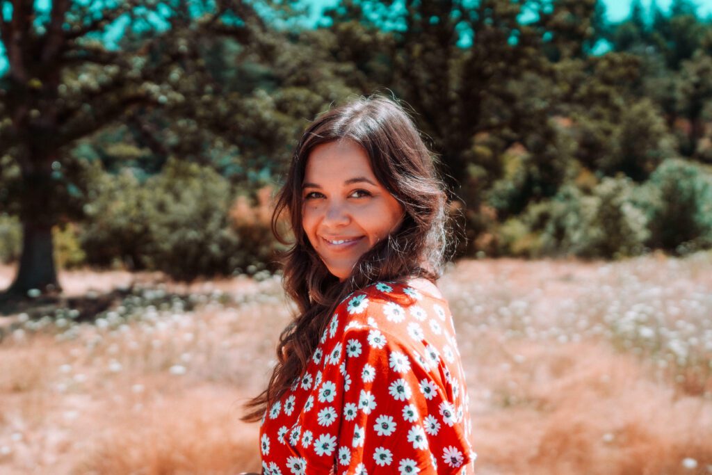 Artist in red floral dress standing in a golden field during a music brand photoshoot in Oregon