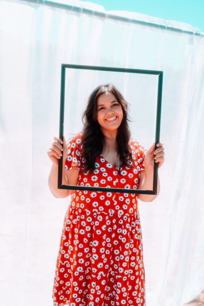 Artist holding a rectangular frame in front of white backdrop for a creative branding shoot near Portland
