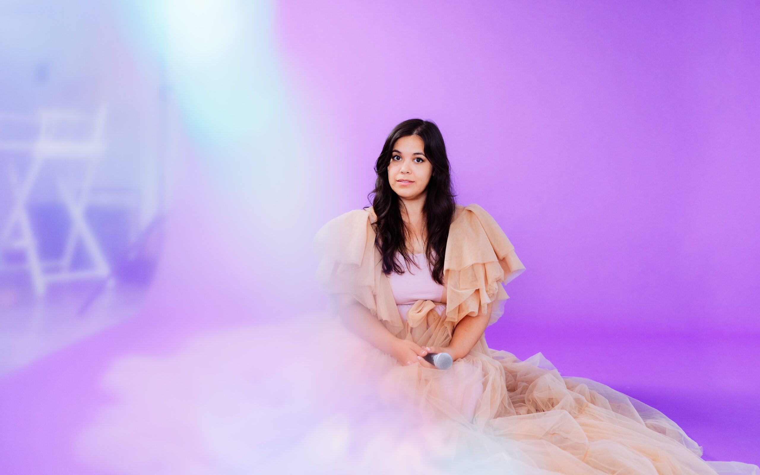 Singer-songwriter sits in a peach tulle gown against a soft purple backdrop during her Portland branding session