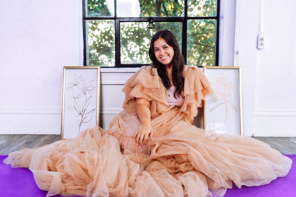 Artist in peach gown seated against a window backdrop in a personal branding shoot for musicians