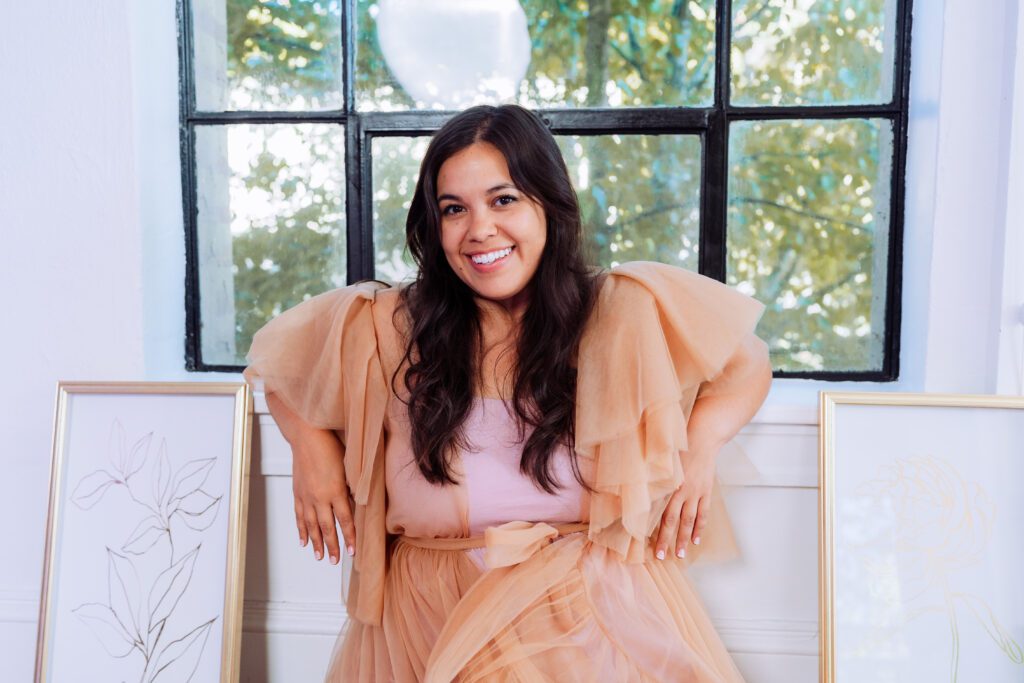 Singer-songwriter laughing in a peach tulle dress framed by large windows during a lifestyle branding shoot