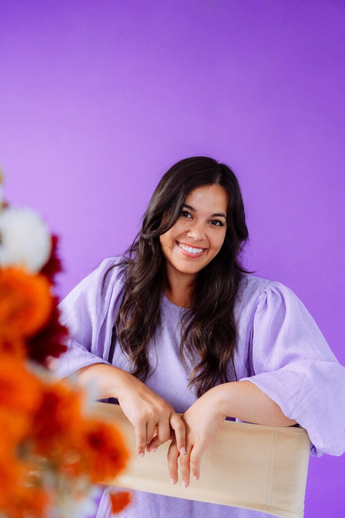 Musician smiling with out-of-focus flowers in the foreground during a branding shoot with a lilac palette