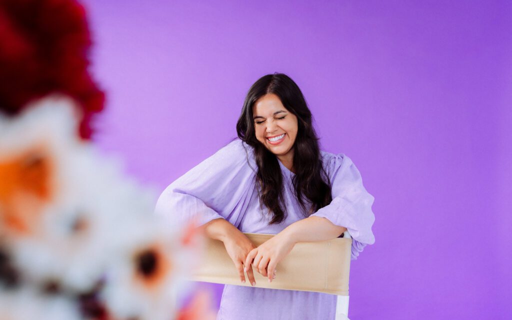 Personal branding photo of a singer seated and smiling in front of a vibrant studio backdrop