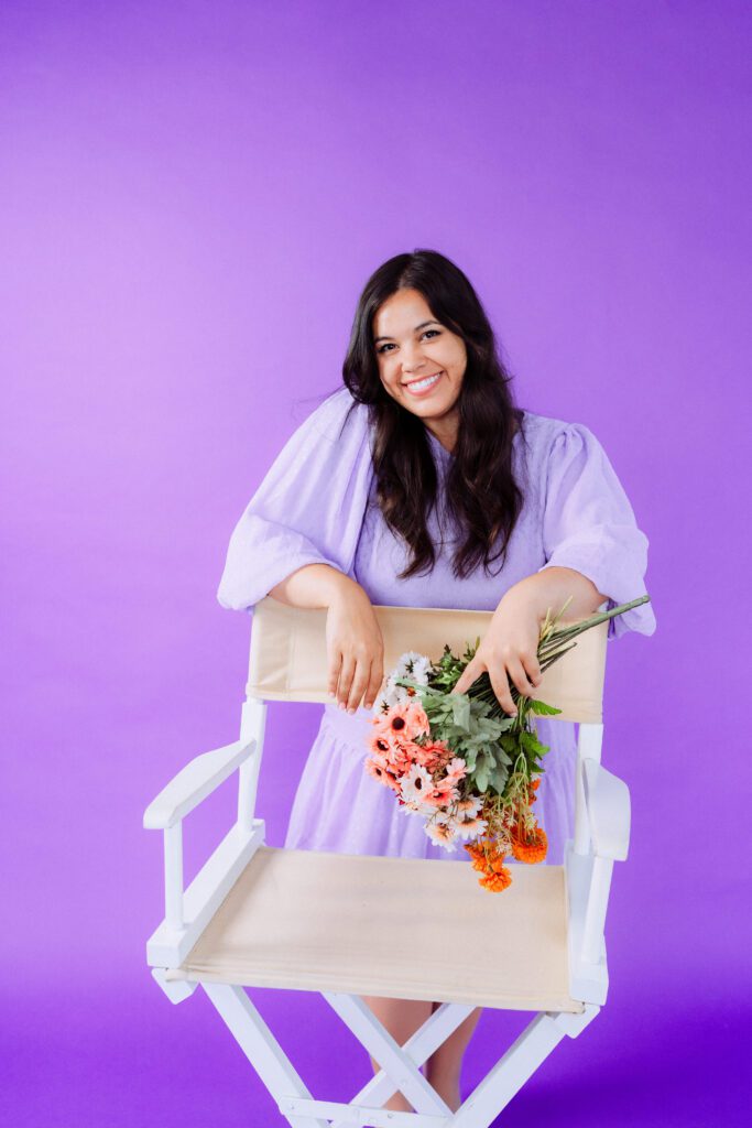 Singer-songwriter seated with flowers on a white chair during a colorful studio branding shoot