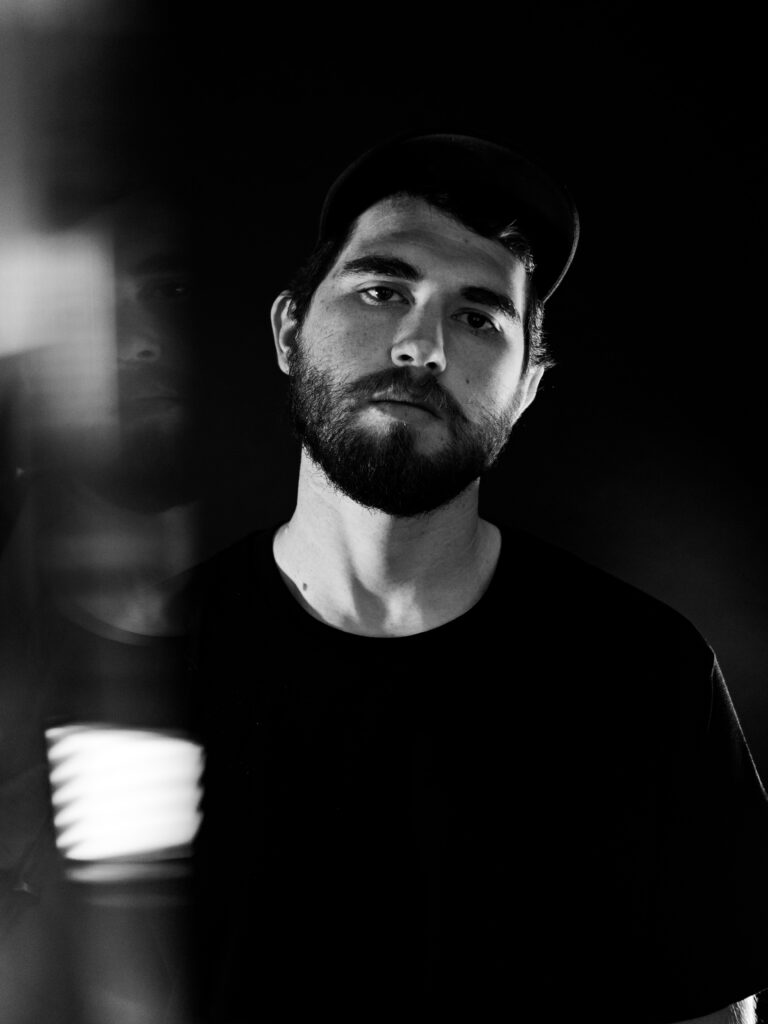 Moody monochrome brand portrait of musician with light trail effect in studio setting