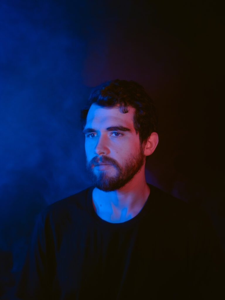 Creative promotional headshot in moody studio lighting for electronic music artist branding