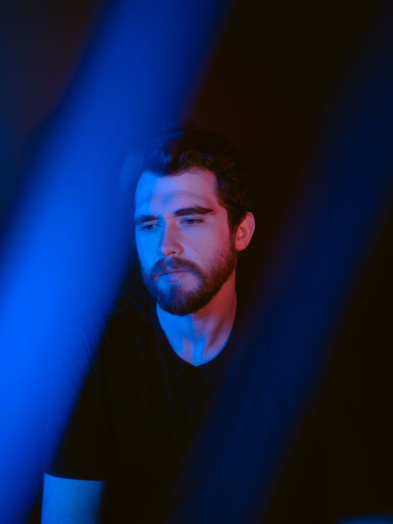 Electronic music artist portrait with surreal blue lighting and movement for promotional visuals