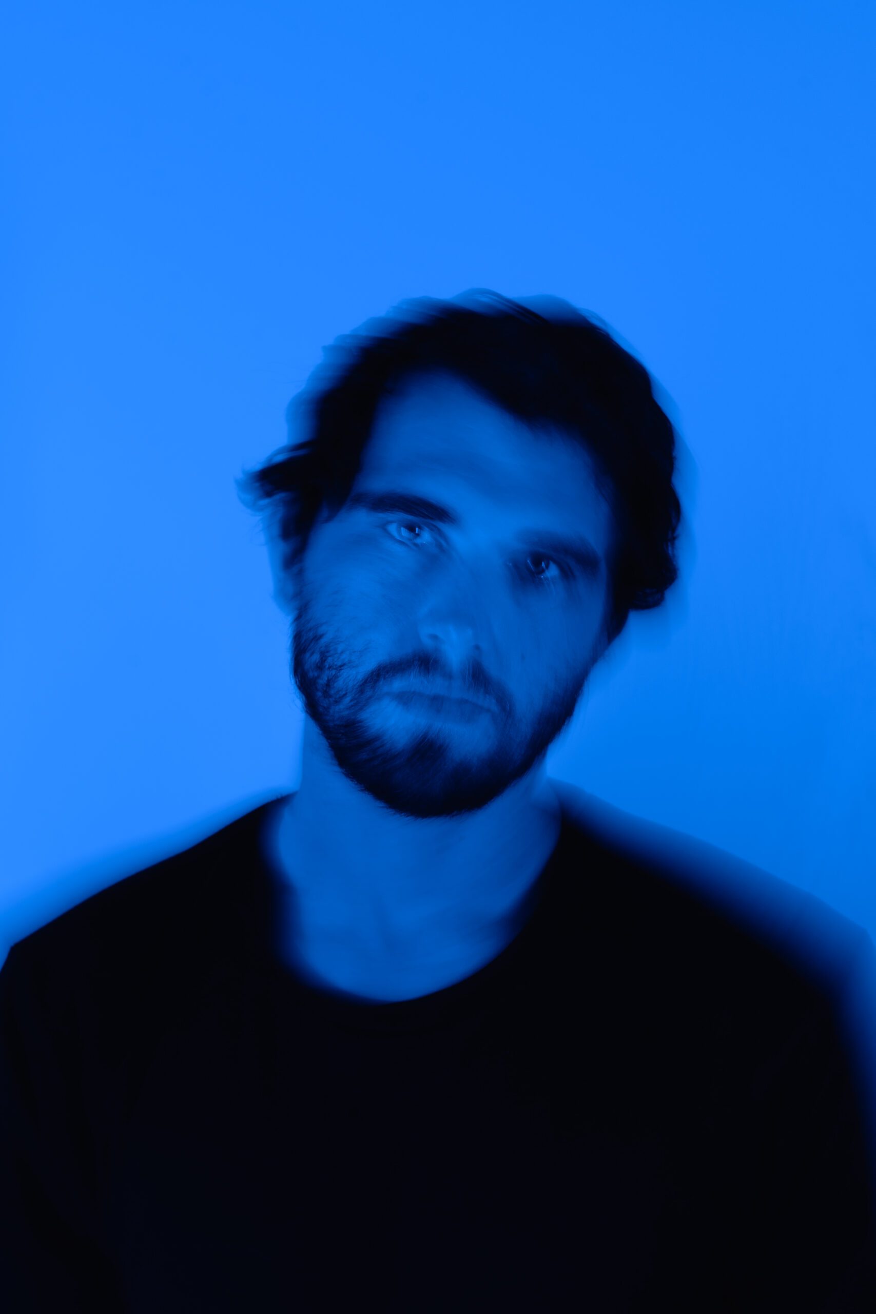 Moody artist headshot in vibrant blue tones for Spotify profile branding