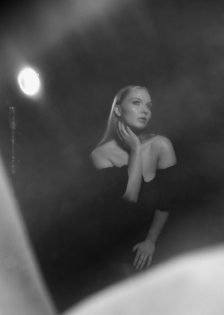 Black and white image of a woman in a classic black dress with spotlight and dreamy haze for a nostalgic cinematic feel