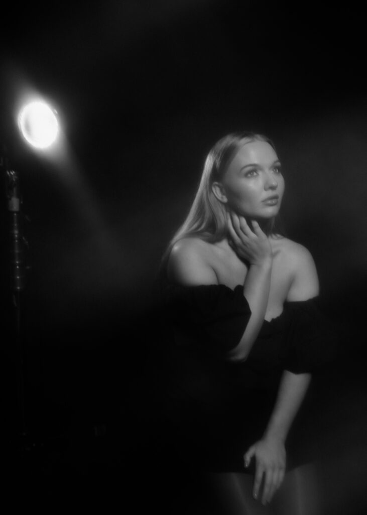 Woman in a studio setting captured through a dreamy haze effect, creating a soft-focus portrait with vintage flair