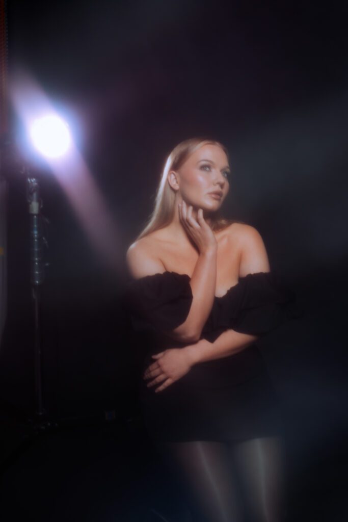 Ethereal black-and-white studio image of a woman gazing off-camera through in-camera haze, styled with timeless monochrome elegance
