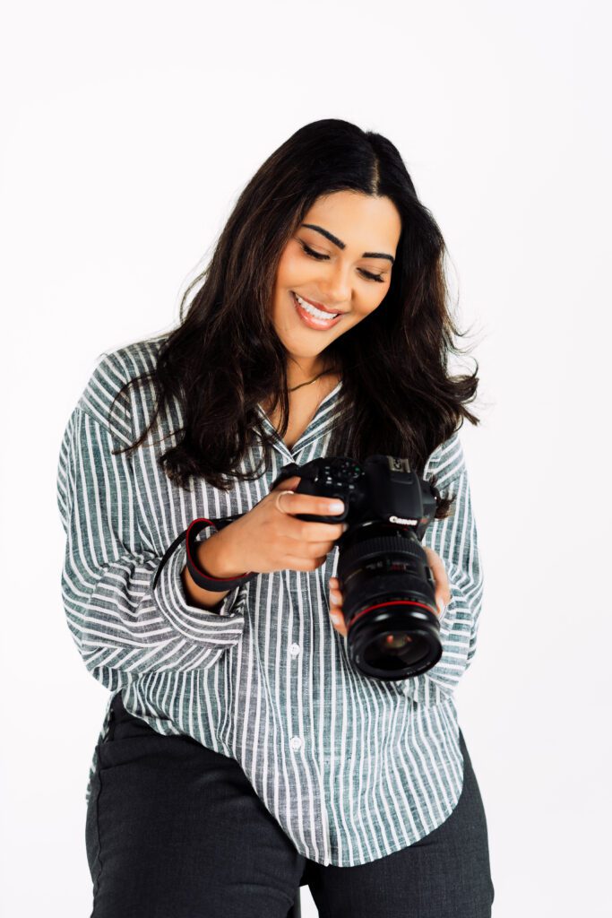 Photographer reviews images on her camera with a smile, showcasing her role as a creative director in her branding session
