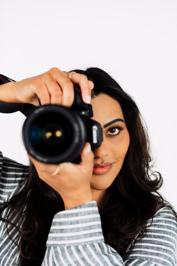 Photographer peers through her camera lens during a confident branding portrait