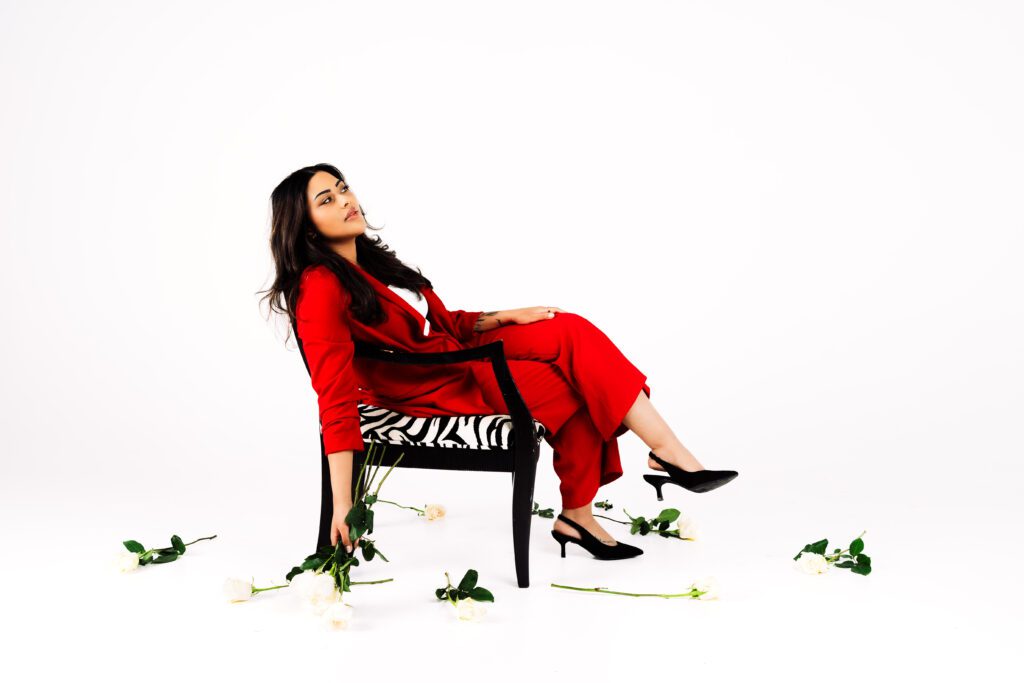 Business Owner reclines in a zebra print chair surrounded by white roses, striking a bold yet thoughtful pose in her branding session